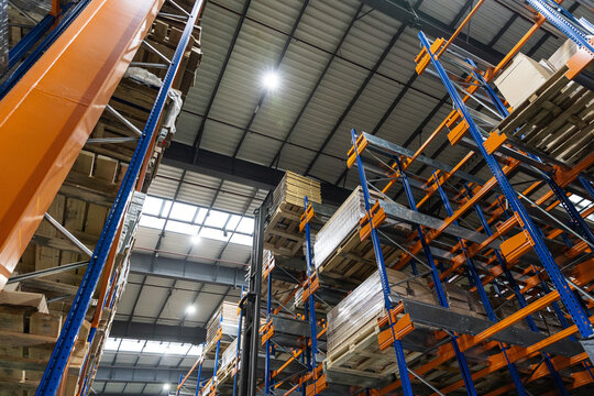 Blue and orange shuttle racking system in warehouse with pallets and boxes 