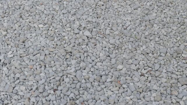 White gravel pebble surface filmed from above. Minimal stone texture background with natural rough pattern.