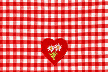 Obraz premium Checkered fabric with red and white pattern featuring a heart with flowers at the center