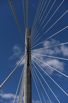 Low angle view of a modern cable-stayed bridge pylon with radiating steel cable