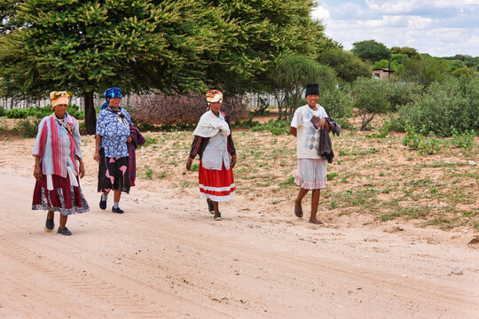 Four Basarwa Women on Dirt Road San people, Botswana. Group walks along a sandy dirt track in the village
