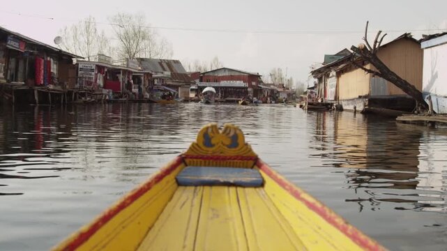 First person view from a yellow boat navigating through the floating market on Dal Lake, Srinagar