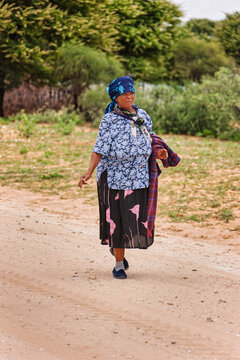 Elderly Basarwa San Woman, Botswana. walks along a sandy dirt track in the village