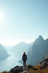 Fototapeta premium Woman hiker walks on rocky cliff edge overlooking calm blue water fjord in Norwegian mountains. Female traveler enjoys scenic vista, summer adventure, active holiday, solo journey.
