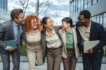 Fototapeta premium Diverse business team embracing each other and smiling outdoors