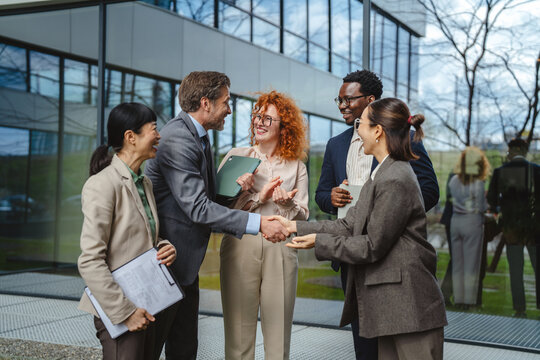 Diverse business team shaking hands achieving success outdoors