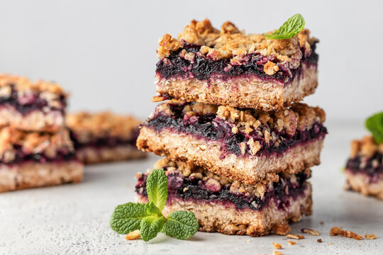 Baked oatmeal bars or crumble squares with fresh blueberry on white textured background. Menu, recipe