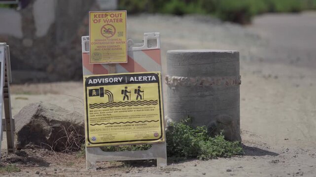 The Border Field State Park sign in San Diego, California, with warning signs alerting visitors of hazardous air and water conditions due to polluted water in the Tijuana River.