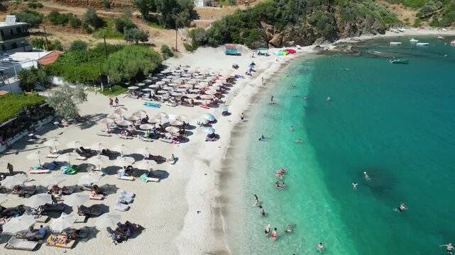 Aerial view of a crowded Mediterranean beach with turquoise water and sunbeds