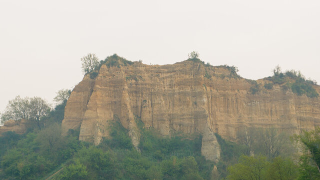 Aerial view of the Valdarno clay cliffs with layered sediment and green vegetation under an overcast sky Florence, Tuscany, Italy.