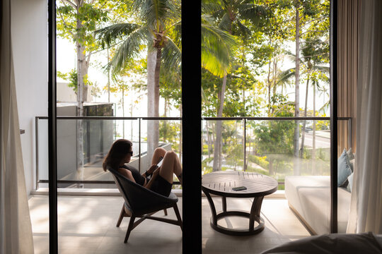 young woman sitting on a chair on a balcony oh the island of Koh Samui in Thailand.