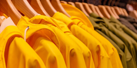 Obraz premium Unique jackets hang on display in a retail store with wooden hangers during a busy shopping day in autumn