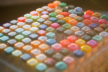 High-angle shot of a vibrant set of professional multi-colored markers arranged on a white workspace, symbolizing creativity, artistic hobby, and design inspiration.
