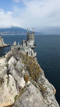 Swallow's nest castle is standing on a steep cliff overlooking the black sea, showcasing its unique neo-gothic architecture and attracting tourists to the crimean coast landmark