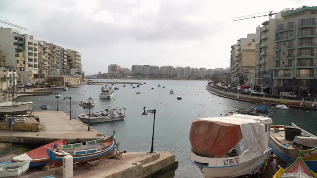 Dramatic contrast of sunlit Spinola Bay and cloudy sky in St. Julian's, Malta, Panning video.