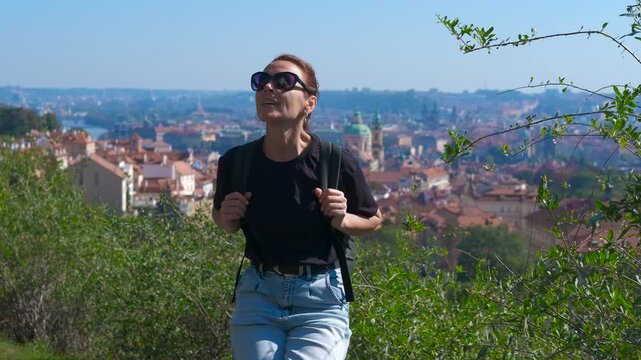 Tourist enjoying prague panorama. Female tourist with sunglasses standing on petrin hill viewpoint, overlooking prague cityscape with zizkov television tower under bright summer sky