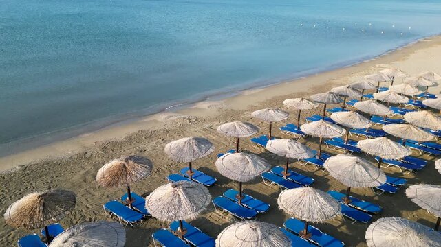 Aerial view of beach umbrellas and blue sunbeds by the sea