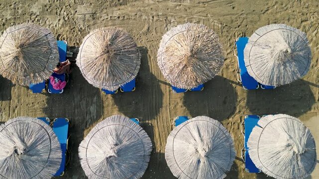 Aerial top down view of straw sun umbrellas on a sandy beach