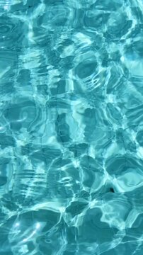 Blue crystal transparent water of a swimming pool abstract background texture. Summer vacation or relax concept,4k vertical video