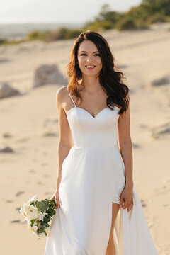 Young bride smiling on beach holding bouquet