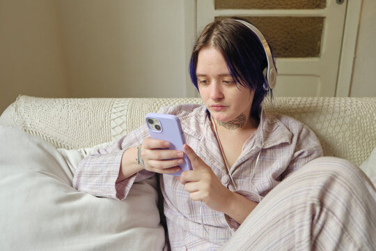 Non-binary autistic person in the couch checking phone in the morning