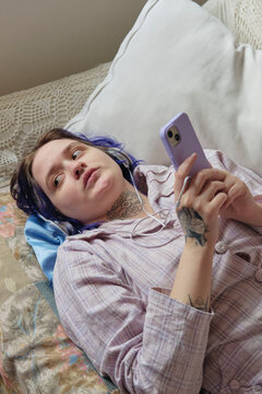Young adult listening to music in the couch in a cozy home