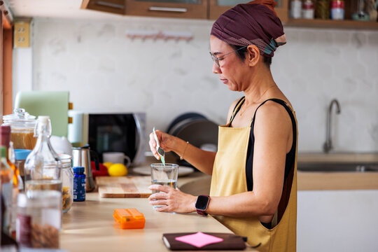 Woman in kitchen pours powdered supplement