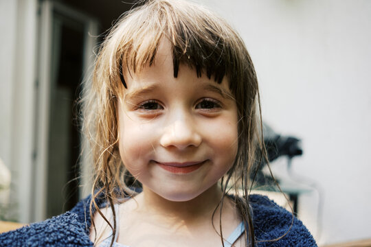 girl with wet hair and covered in towel smiling into camera