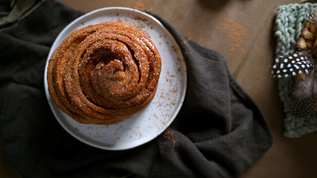 Top View of Freshly Baked Cinnamon Roll on White Plate with Dark Linen