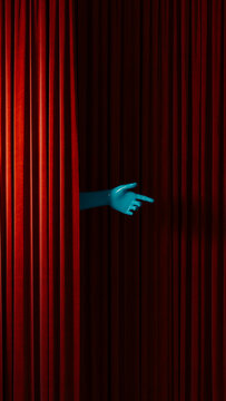 Hand reaches out from behind red curtain in theater setting