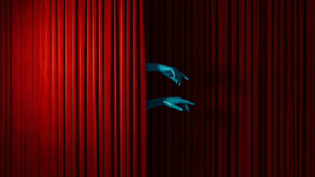 Hands emerges from behind red curtain on a stage during a show