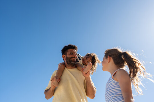 A father and daughter laugh together while spending time by the ocean