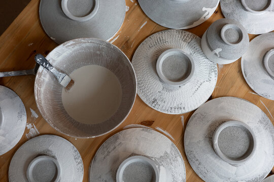 Handmade Ceramic Plates Being Glazed in Pottery Workshop