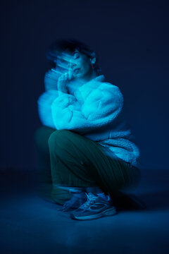 Person in blue light poses with thoughtful expression