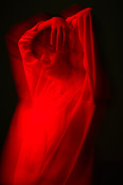 Model poses in red light with hands on head