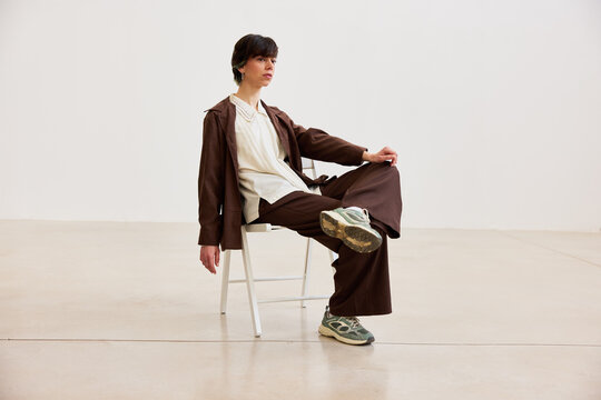Model sits on chair in gallery space during fashion event
