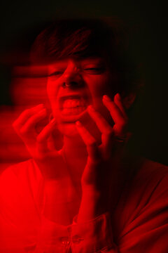 Person expressing emotion with hands in red light at night
