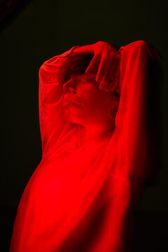 Person poses with hands above head in red light