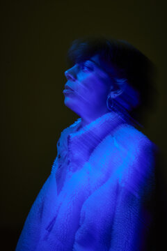 Woman with blue light on her face in dark setting at night
