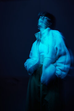 Model poses wearing a fluffy jacket in blue lighting backdrop