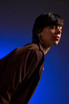 Portrait of a person posing against a blue backdrop
