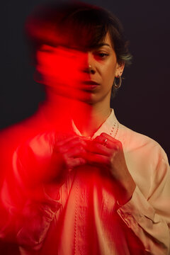 Woman holding hands in front of blurred red light at night