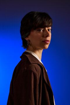 Woman poses against a blue background in a studio setting