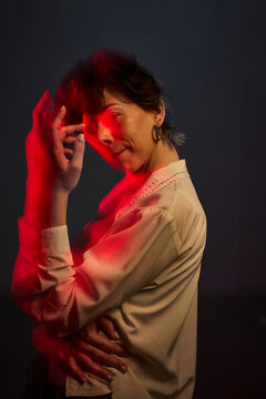 Woman poses with red light in a dark setting during a photoshoot