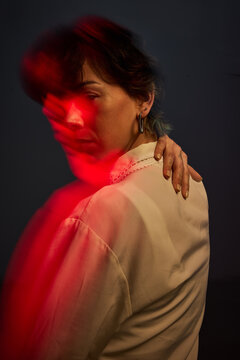Woman with red light behind her in a dark setting