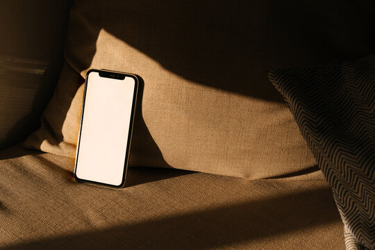 Phone With White Screen Rests on a Couch in a Warm Afternoon Light