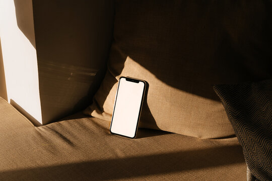 Phone With White Screen Rests on a Couch in a Warm Afternoon Light