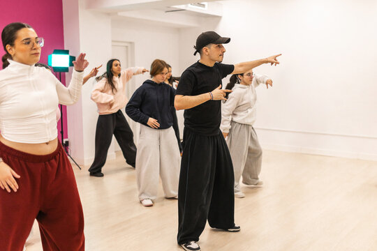 Male instructor teaching urban dance to teenagers in studio