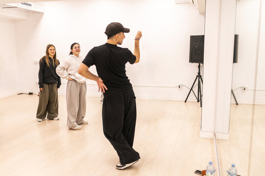 Male instructor teaching urban dance to teenagers in studio