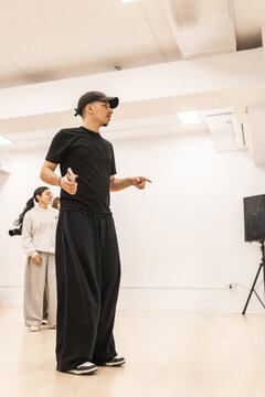 Male instructor teaching urban dance to teenagers in studio